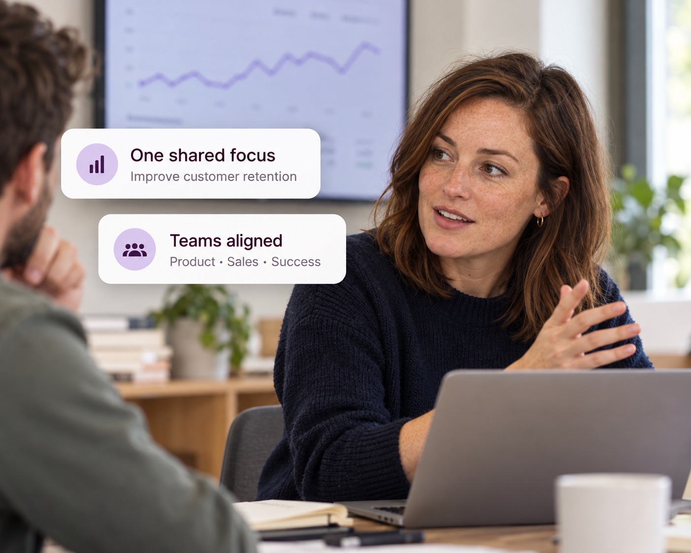 A finance leader talking with a colleague in front of a chart, with Decided cards showing one shared focus and teams aligned