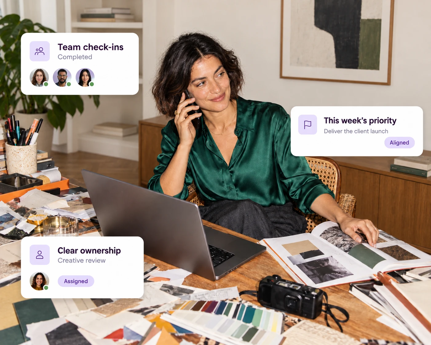 An agency owner on a call at a desk covered in moodboards and color swatches, with Decided cards showing team check-ins completed, this week's priority aligned and clear ownership of the creative review